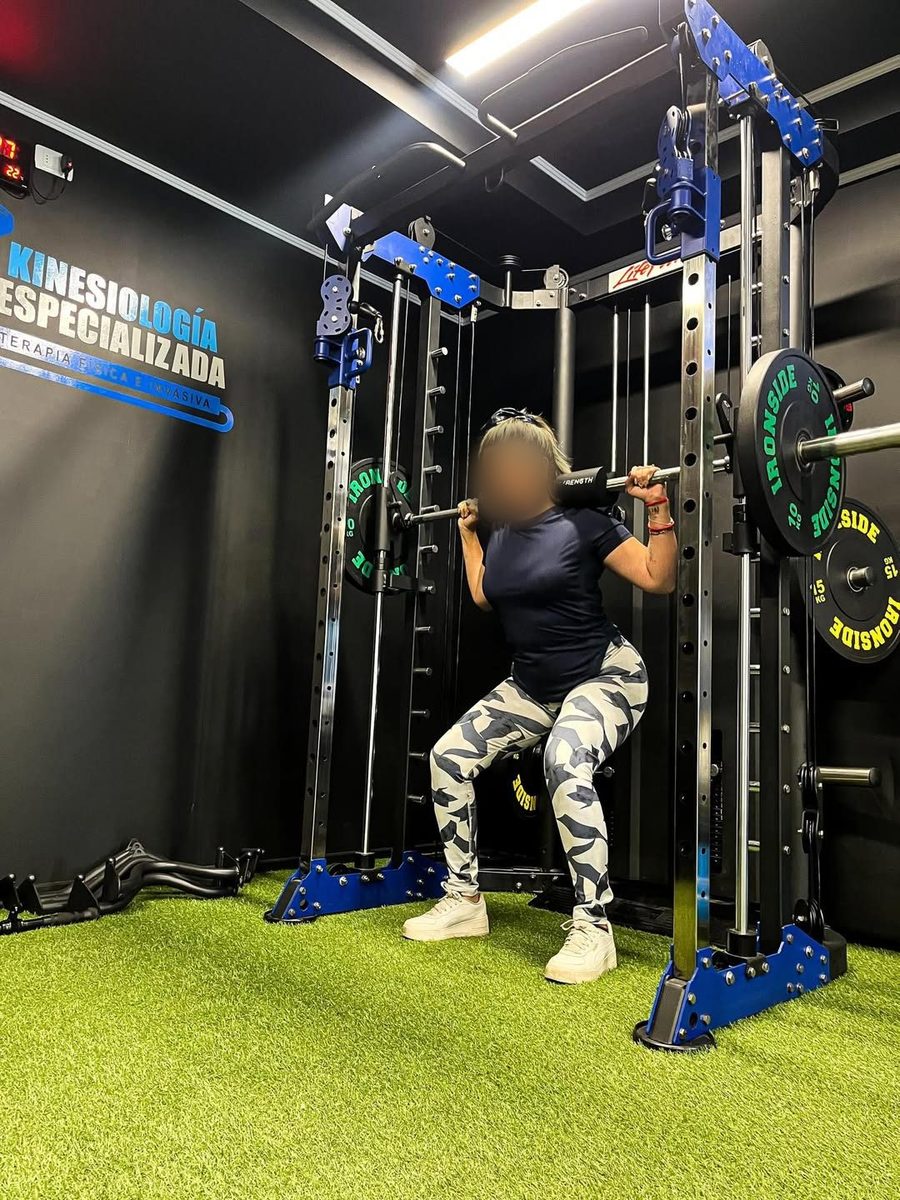 Paciente entrenando sentadilla en el rack del centro